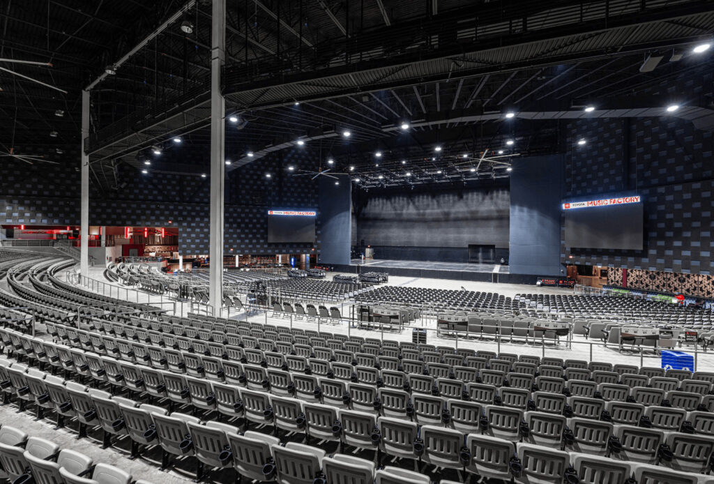 Empty indoor concert venue with rows of gray seats, large stage, and Toyotas screens displaying Music in Columbus Ohio.