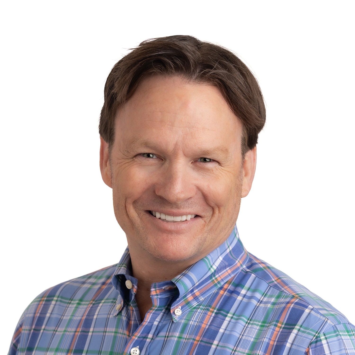 Smiling Nicky W. Anderson with short brown hair in a blue plaid shirt poses before a white background.