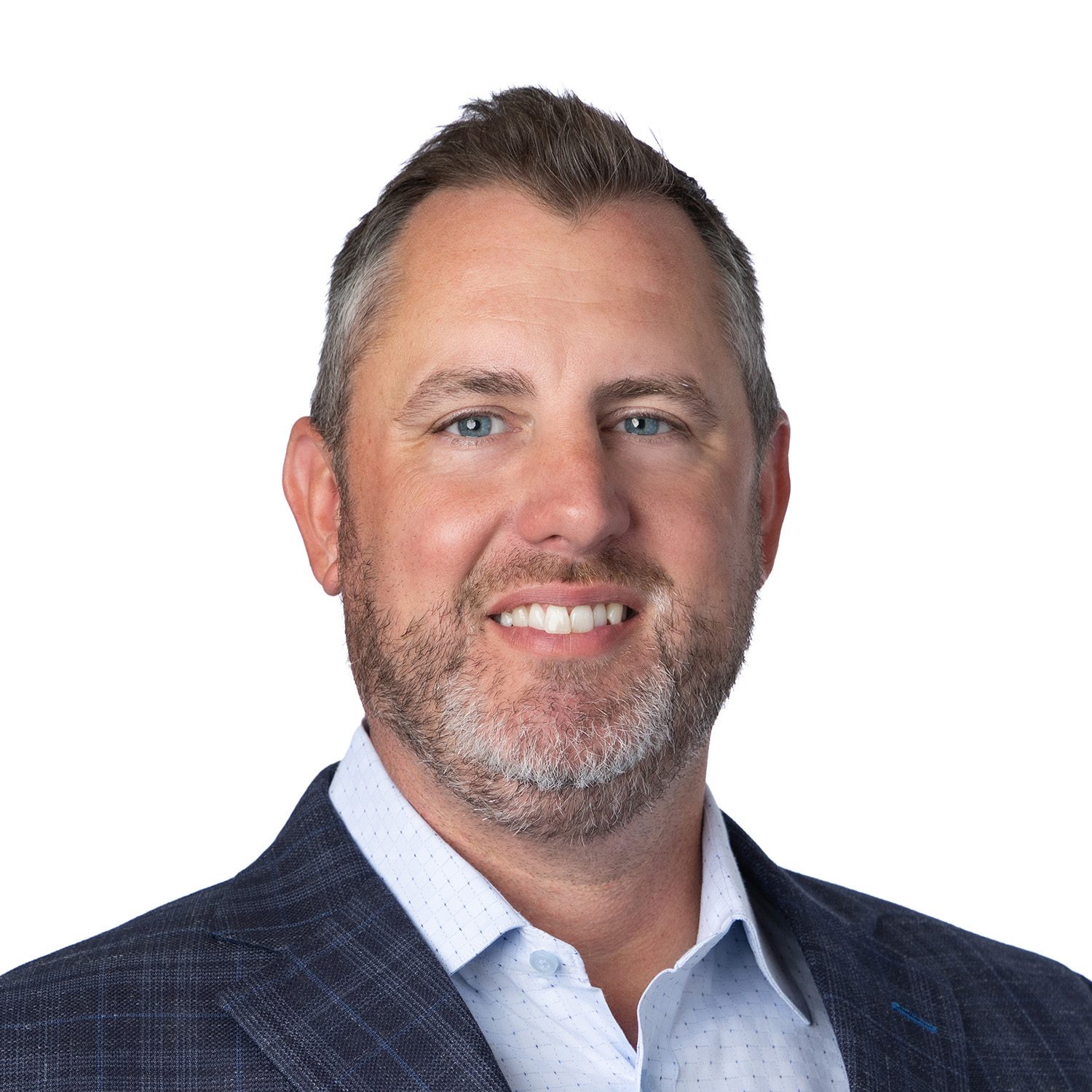 Smiling man with short hair and beard, wearing a blue blazer and white shirt, on a white background.
