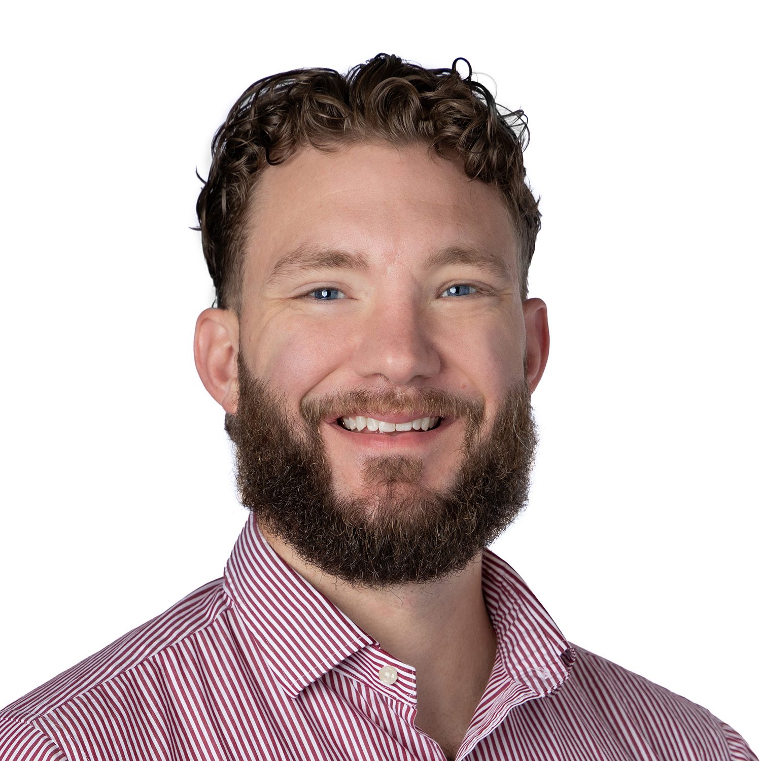 Smiling man with a beard and curly hair, wearing a red and white striped shirt, on a white background.