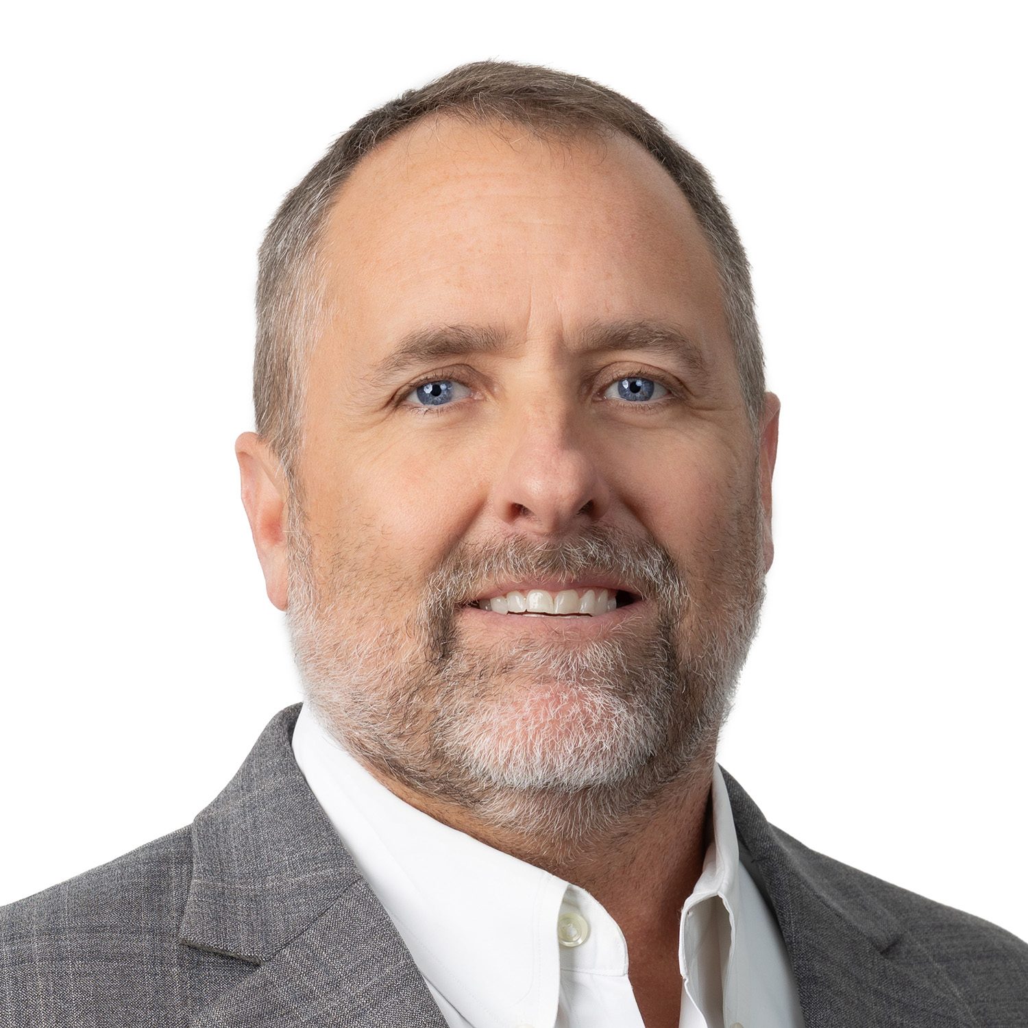 Smiling man with short brown hair and beard, wearing a gray suit jacket and white shirt, on a white background.